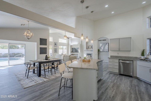 kitchen featuring ceiling fan with notable chandelier, sink, hanging light fixtures, stainless steel dishwasher, and a kitchen island