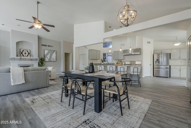 dining area with high vaulted ceiling, visible vents, light wood-style floors, and a fireplace