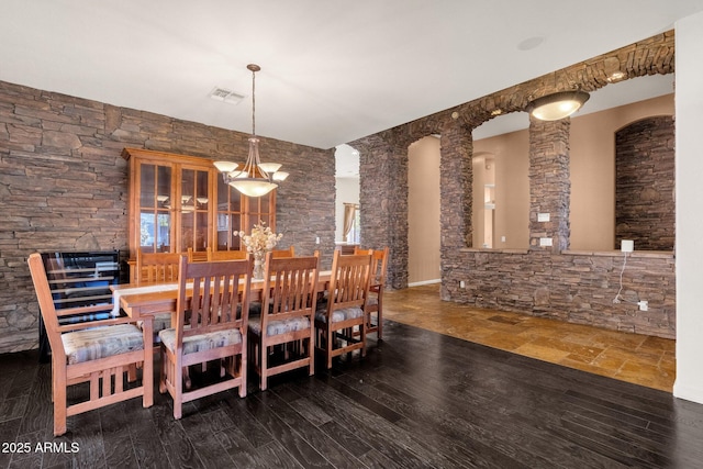 dining area featuring dark wood-type flooring and decorative columns