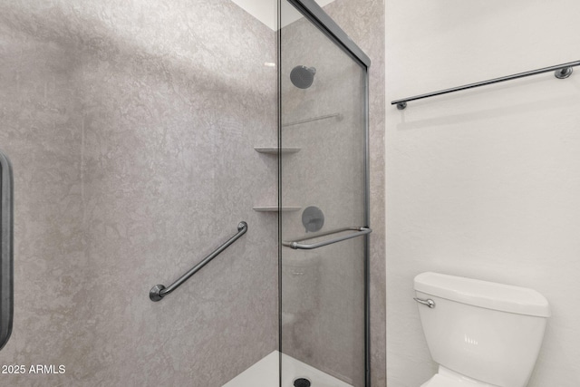 bathroom featuring a shower with shower door and toilet