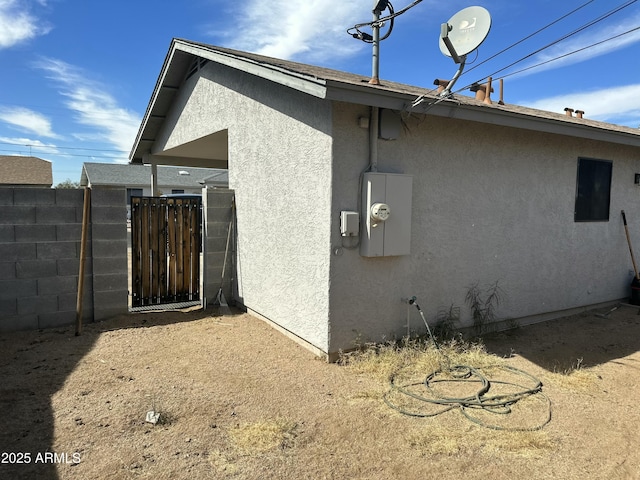 view of property exterior featuring fence, a gate, and stucco siding