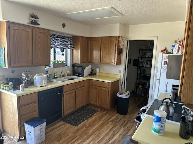 kitchen with light countertops, brown cabinetry, a sink, wood finished floors, and dishwasher