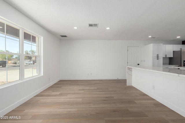 unfurnished living room with baseboards, visible vents, light wood finished floors, and recessed lighting