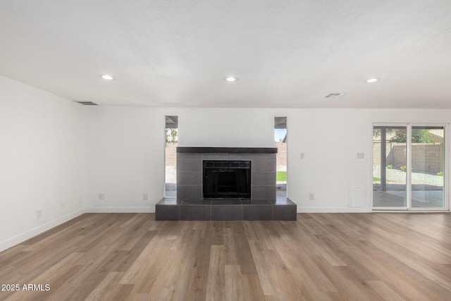 unfurnished living room with baseboards, wood finished floors, and plenty of natural light