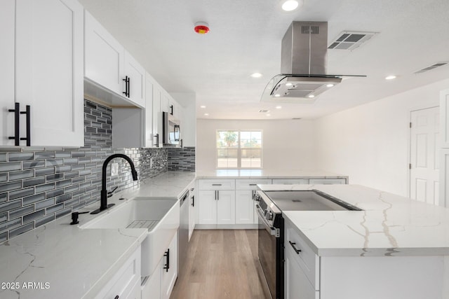 kitchen with decorative backsplash, stainless steel appliances, light wood-style floors, a center island, and visible vents