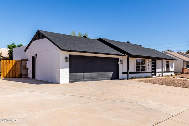 view of front facade featuring driveway, a shingled roof, stucco siding, and a garage