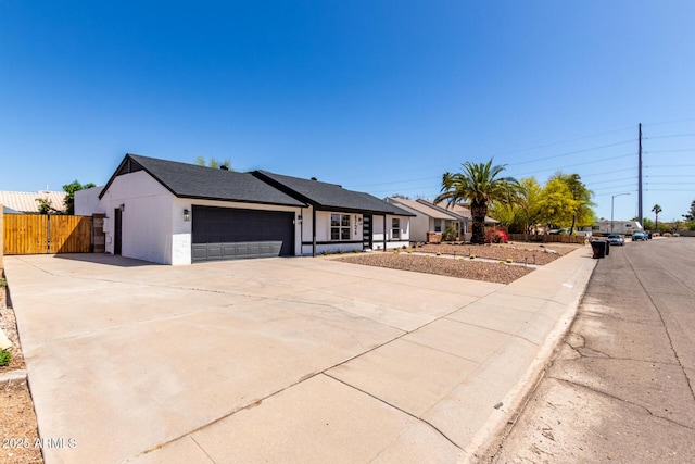ranch-style home with concrete driveway, stucco siding, an attached garage, and fence