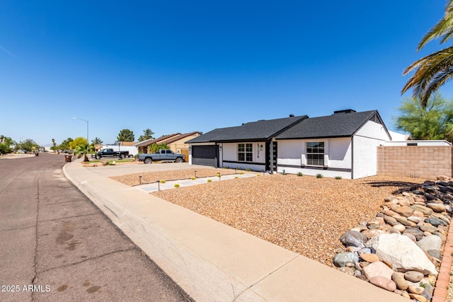 ranch-style house with stucco siding, fence, concrete driveway, and a garage