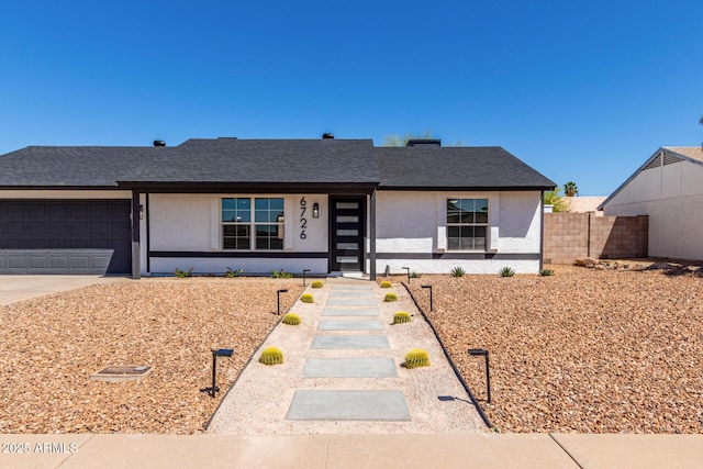 ranch-style home featuring a garage, roof with shingles, concrete driveway, stucco siding, and fence