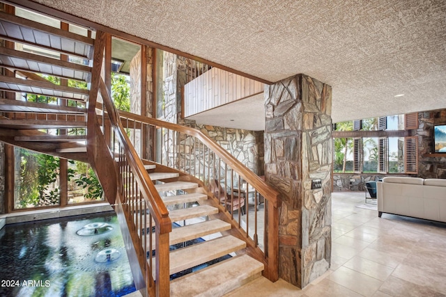 stairway with a healthy amount of sunlight and a textured ceiling