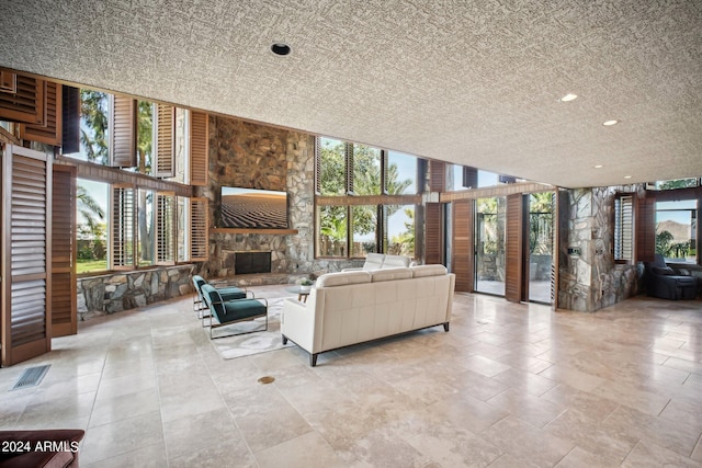 unfurnished living room with a wall of windows, a stone fireplace, and plenty of natural light