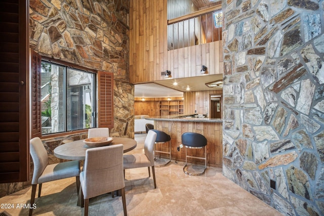 dining room featuring wooden walls and a high ceiling