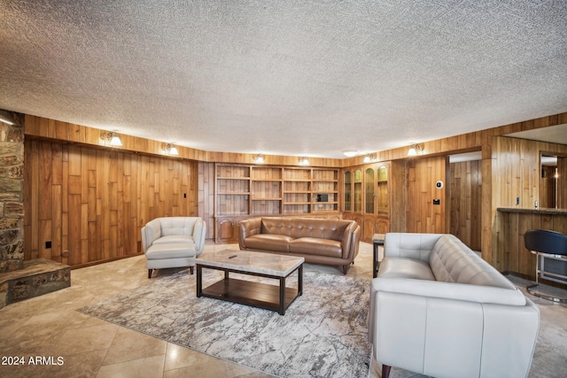 living room with wooden walls, tile patterned flooring, and a textured ceiling