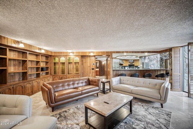 living room with a textured ceiling, plenty of natural light, and wooden walls