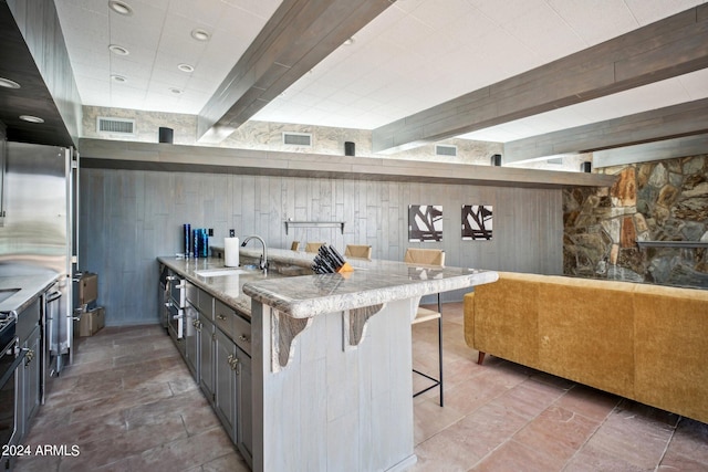 kitchen featuring a kitchen breakfast bar, stove, wood walls, and sink