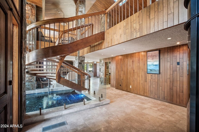 stairs with a high ceiling and wood walls