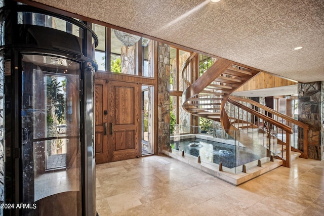 entrance foyer featuring wooden walls and a textured ceiling