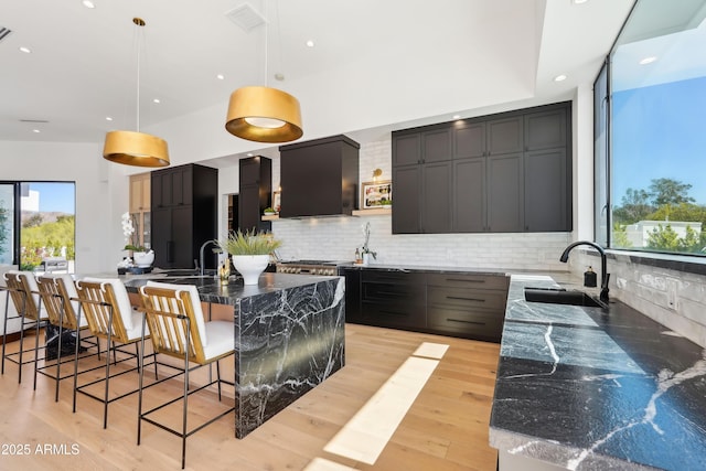 kitchen featuring visible vents, a sink, decorative backsplash, and dark stone countertops