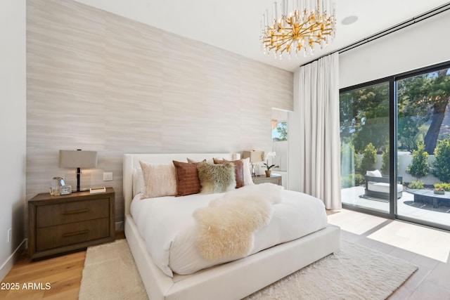 bedroom with access to outside, a chandelier, and light wood-style floors