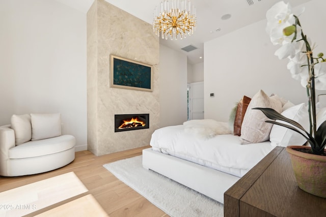 bedroom featuring an inviting chandelier, visible vents, wood finished floors, baseboards, and a high end fireplace