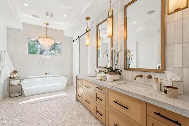 bathroom with double vanity, visible vents, tile walls, a sink, and a soaking tub
