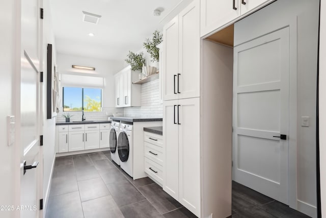 laundry room with recessed lighting, dark tile patterned flooring, washing machine and clothes dryer, a sink, and cabinet space