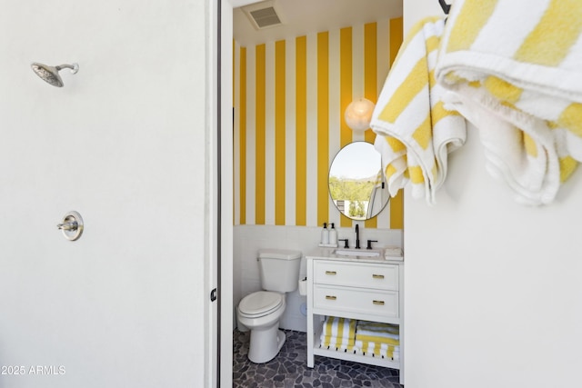 bathroom with vanity, toilet, a wainscoted wall, wallpapered walls, and visible vents
