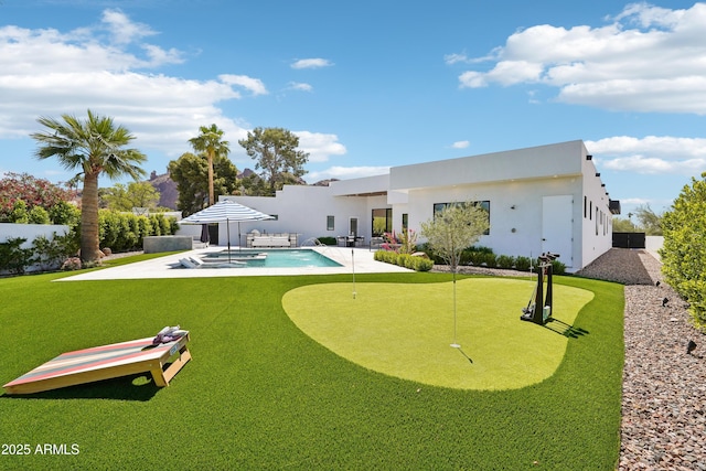 rear view of property featuring a patio, a jacuzzi, stucco siding, and a fenced in pool