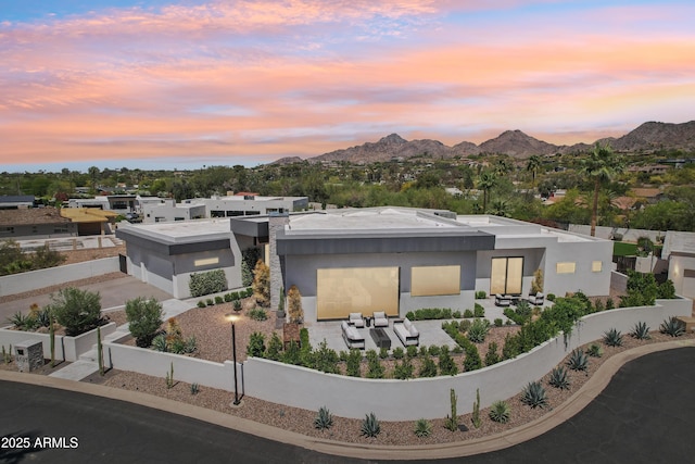 view of front of home featuring driveway, a mountain view, a fenced backyard, and stucco siding