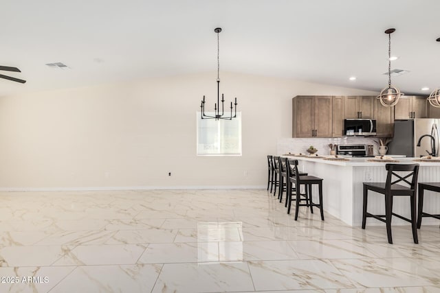 kitchen with marble finish floor, a kitchen bar, appliances with stainless steel finishes, and decorative backsplash