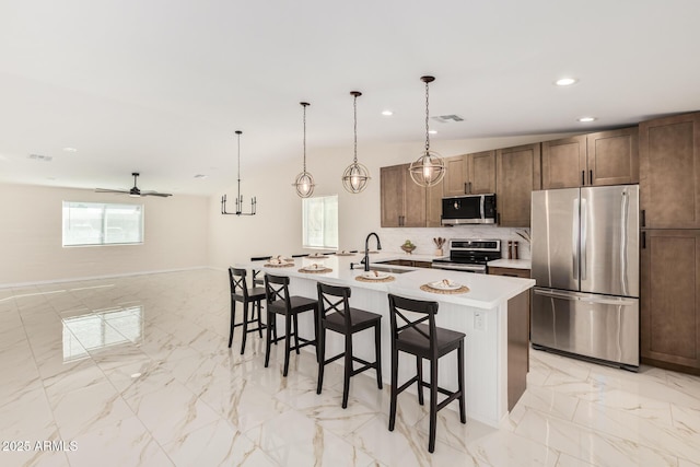 kitchen with stainless steel appliances, a sink, visible vents, light countertops, and a kitchen bar