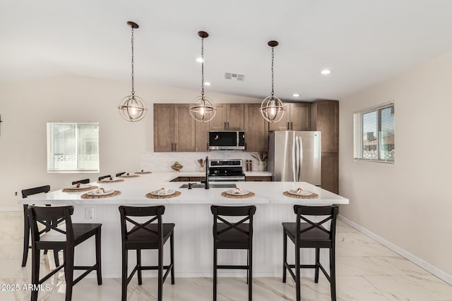 kitchen featuring visible vents, appliances with stainless steel finishes, a breakfast bar area, marble finish floor, and light countertops