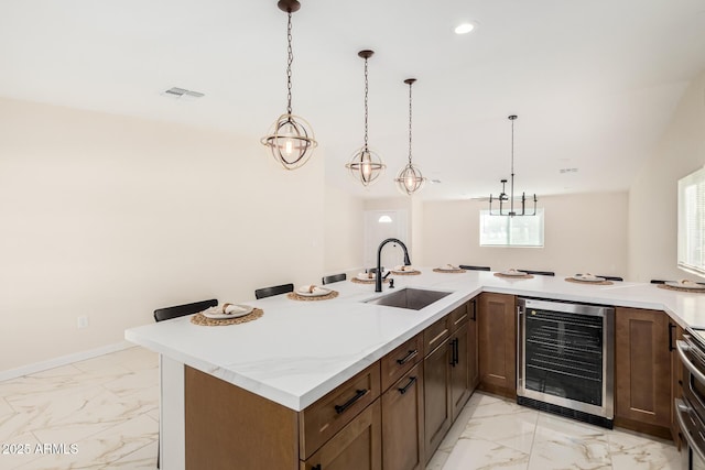 kitchen featuring marble finish floor, wine cooler, visible vents, and a sink