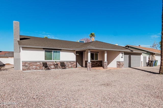 view of front facade featuring stone siding, an attached garage, driveway, and stucco siding