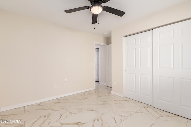 unfurnished bedroom featuring marble finish floor, a closet, a ceiling fan, and baseboards