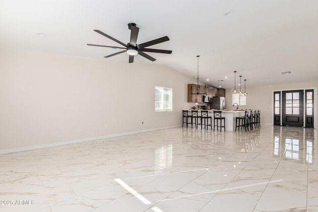 unfurnished living room with lofted ceiling, marble finish floor, baseboards, and ceiling fan with notable chandelier