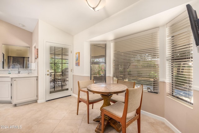 tiled dining room with vaulted ceiling and sink