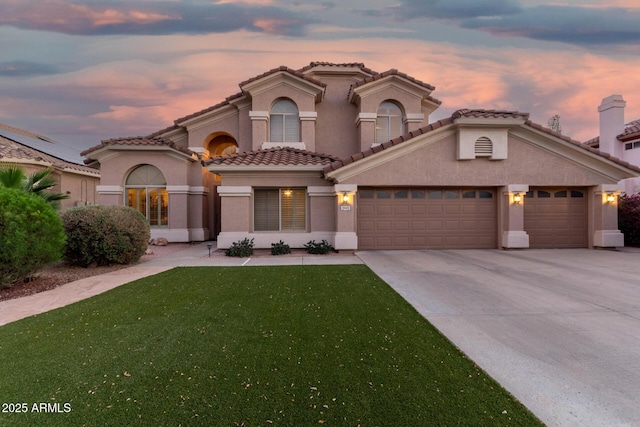 mediterranean / spanish home featuring a garage, concrete driveway, a yard, and stucco siding