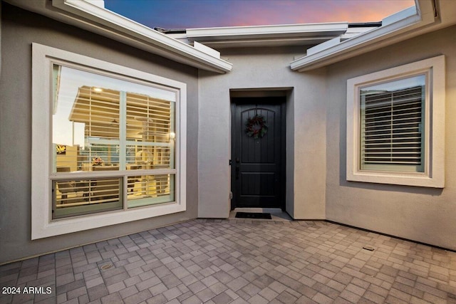 exterior entry at dusk featuring a patio