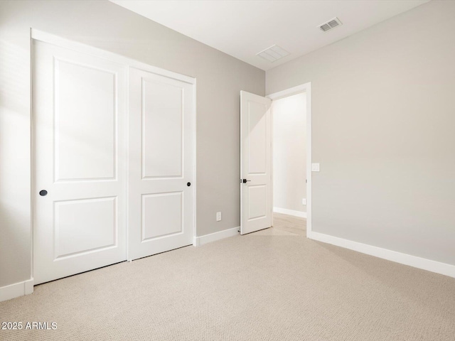 unfurnished bedroom featuring light colored carpet and a closet