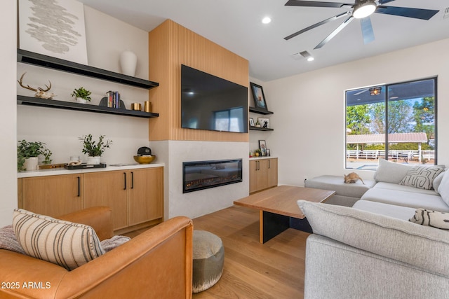 living room featuring ceiling fan and light hardwood / wood-style flooring