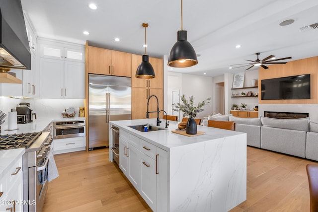 kitchen with sink, decorative light fixtures, a center island with sink, appliances with stainless steel finishes, and white cabinets