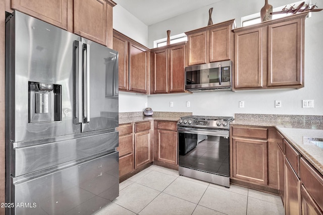 kitchen featuring light stone counters, stainless steel appliances, and light tile patterned floors