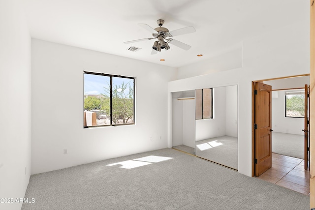 unfurnished bedroom with a closet, multiple windows, visible vents, and carpet