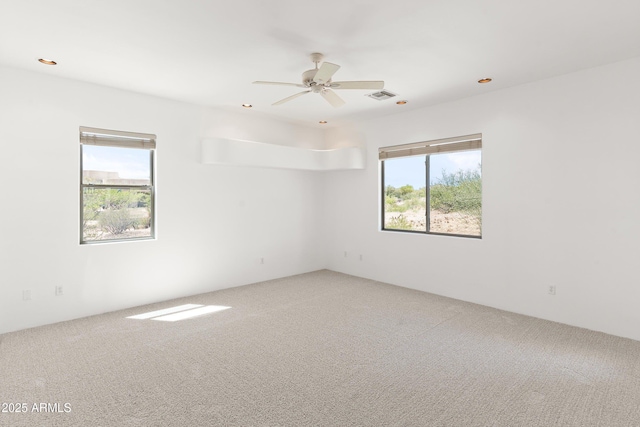 carpeted empty room featuring a ceiling fan, visible vents, and recessed lighting