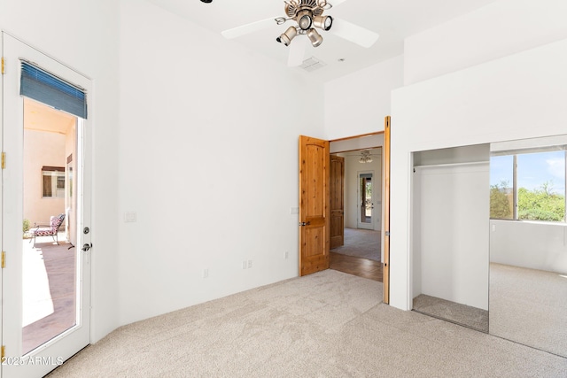 unfurnished bedroom with a ceiling fan, a towering ceiling, carpet floors, and a closet
