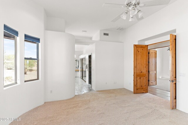 tiled empty room featuring visible vents, carpet floors, and ceiling fan