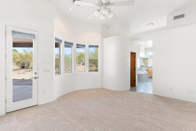 spare room featuring carpet floors, visible vents, a ceiling fan, and a healthy amount of sunlight