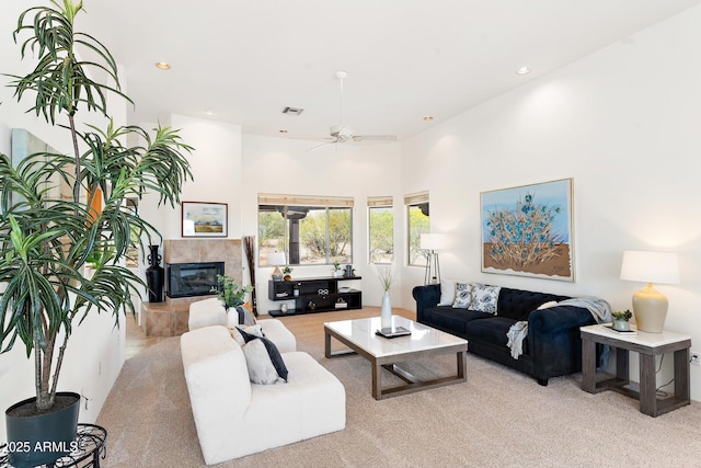 living area with visible vents, recessed lighting, a ceiling fan, a high ceiling, and a tile fireplace