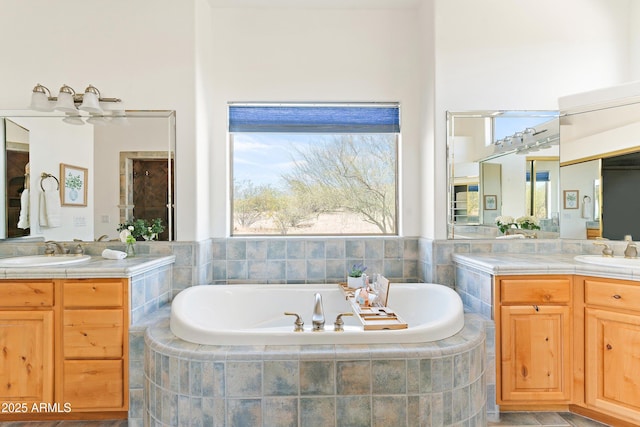 full bath with a bath, a sink, and two vanities